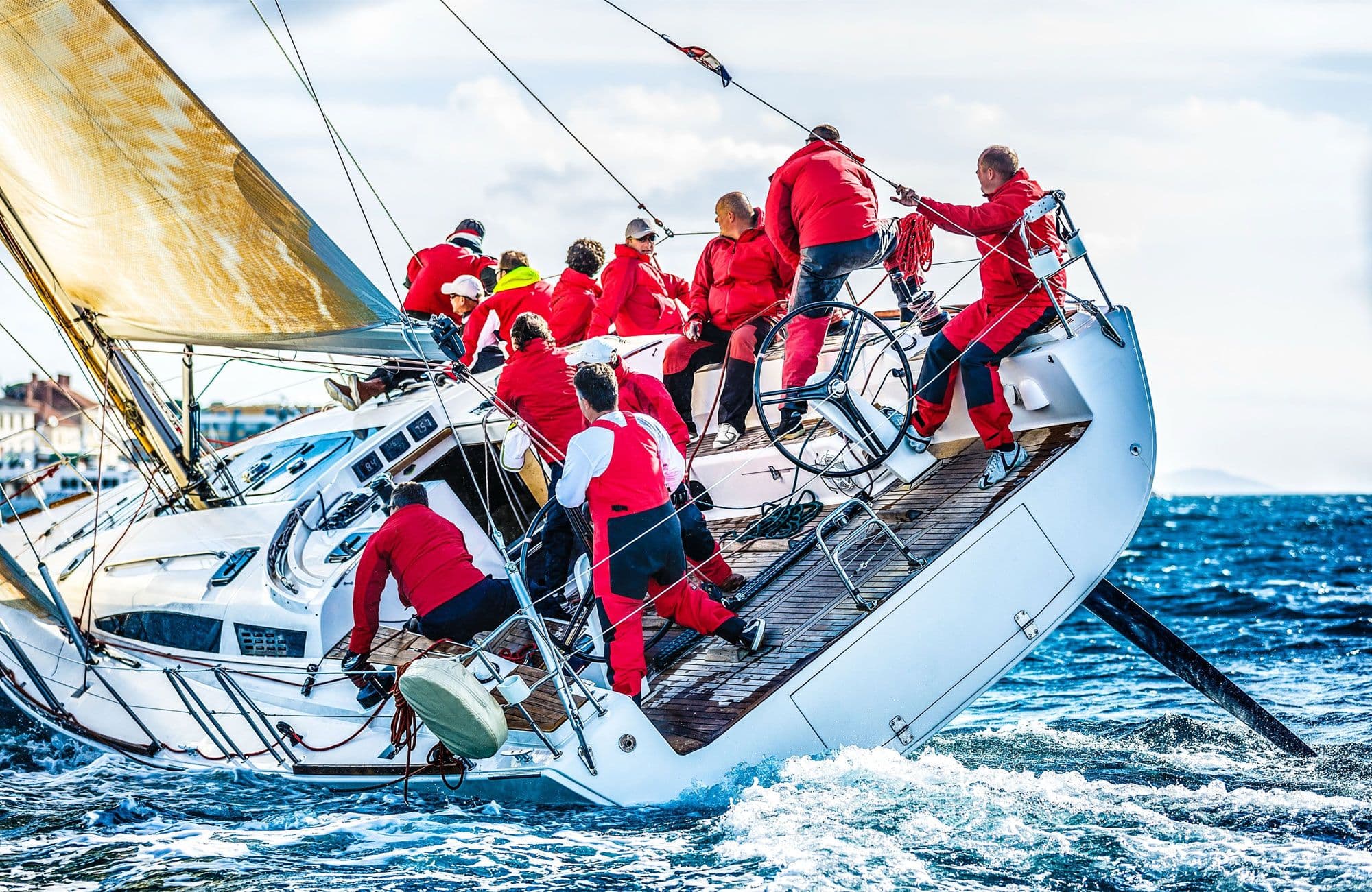 The crew on a sailing yacht works together on deck, handling the sails and lines in strong winds on the open sea.